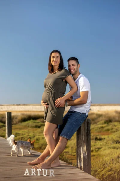 Küçük köpeği olan mutlu hamile çift.