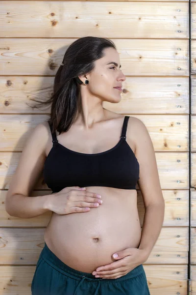 Mujer embarazada posa con las manos en el vientre — Foto de Stock