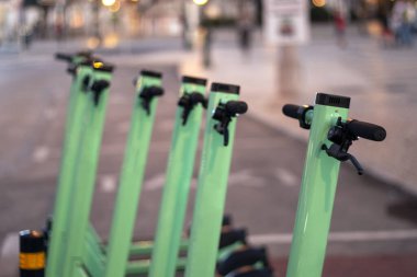 Şehirde park edilmiş yeşil elektrikli scooter 'lar..