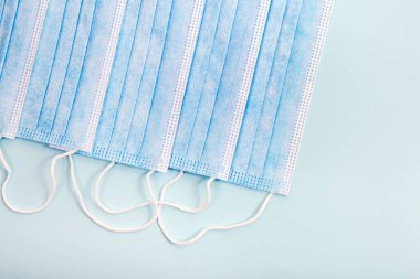 Açık mavi arka planda izole edilmiş tıbbi koruyucu maskeler..