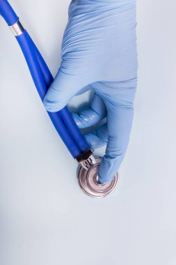 Doktor, açık mavi arka planda steteskoplu mavi eldivenleri teslim et..