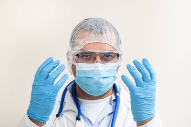Beyaz arka planda beyaz önlüklü, steteskop, koruyucu giysi ve beyaz önlüklü beyaz bir doktor..