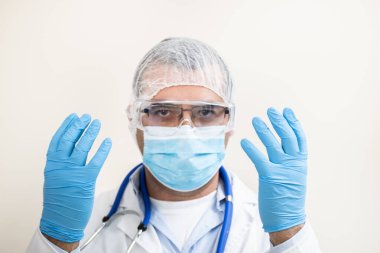 Beyaz arka planda beyaz önlüklü, steteskop, koruyucu giysi ve beyaz önlüklü beyaz bir doktor..
