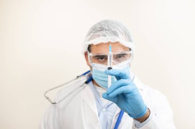 Yumuşak odaklı arka planda şırıngası olan beyaz bir doktor görüntüsü.