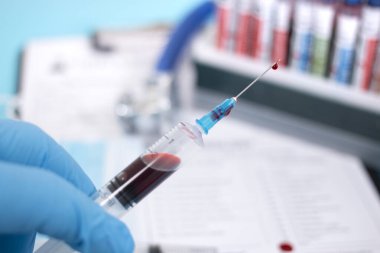 Doktor ellerinde analiz için kan örneği alınması için tıbbi bir şırınga tutuyor..