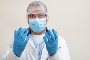 Beyaz arka planda beyaz önlüklü, steteskop, koruyucu giysi ve beyaz önlüklü beyaz bir doktor..