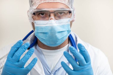 Beyaz arka planda beyaz önlüklü, steteskop, koruyucu giysi ve beyaz önlüklü beyaz bir doktor..
