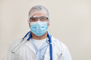 Beyaz arka planda beyaz önlüklü, steteskop, koruyucu giysi ve beyaz önlüklü beyaz bir doktor..