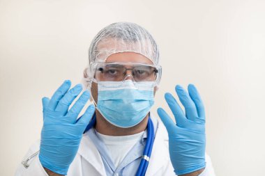 Beyaz arka planda beyaz önlüklü, steteskop, koruyucu giysi ve beyaz önlüklü beyaz bir doktor..