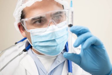 Yumuşak odaklı arka planda şırıngası olan beyaz bir doktor görüntüsü.