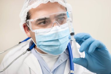 Yumuşak odaklı arka planda şırıngası olan beyaz bir doktor görüntüsü.