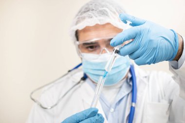 Beyaz arka planda şırıngası ve test tüpü olan beyaz bir doktor görüntüsü.