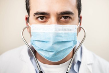 Beyaz arka planda steteskop ve yüz maskesi olan beyaz bir doktor..