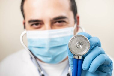 Beyaz arka planda steteskop ve yüz maskesi olan beyaz bir doktor..