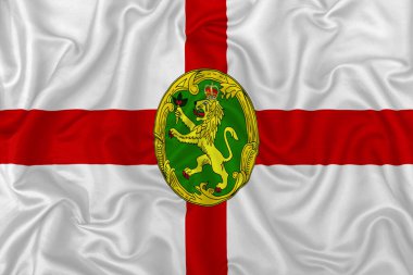 Dalgalı ipek kumaş arka planında Alderney adaları bayrağı.