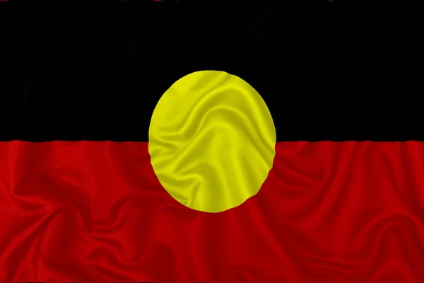 Aboriginal Australia flag on wavy silk textile fabric background.