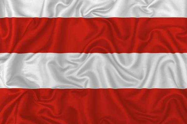 Brno city  flag on wavy silk textile fabric background.