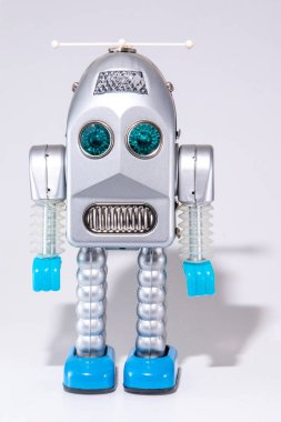 Gri arka planda izole edilmiş eski model bir robot oyuncak..
