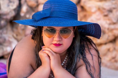 Siyah bikinili ve kumsalda koyu renk güneş gözlüklü güzel, şehvetli bir kadın..