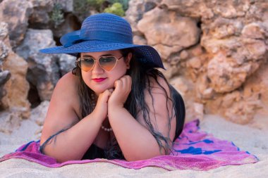 Siyah bikinili ve kumsalda koyu renk güneş gözlüklü güzel, şehvetli bir kadın..