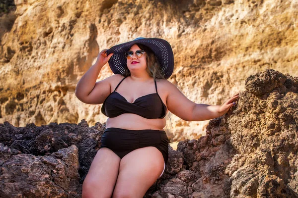 beautiful sensual woman with black bikini and dark shades on the beach.