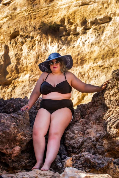 beautiful sensual woman with black bikini and dark shades on the beach.