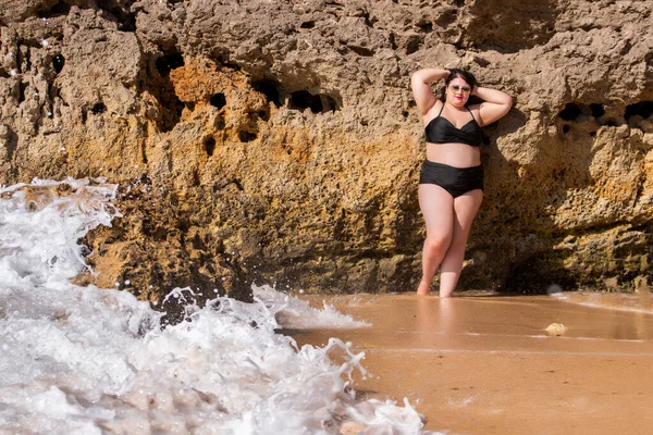 beautiful sensual woman with black bikini and dark shades on the beach.
