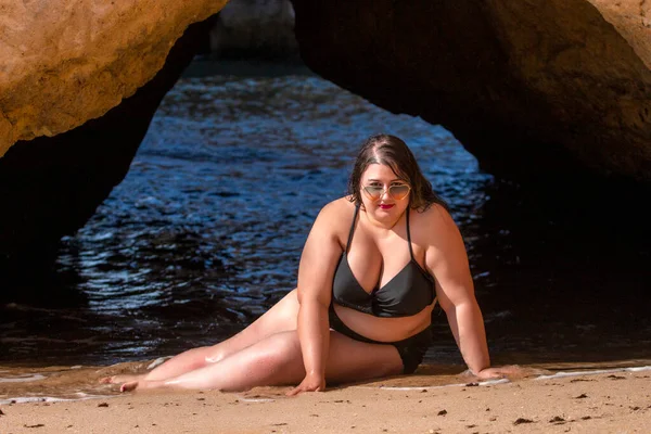 beautiful sensual woman with black bikini and dark shades on the beach.