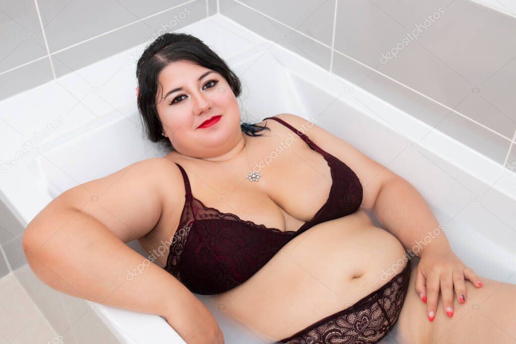 woman in sensual dark red lingerie on a milky bathtub.