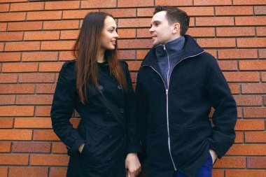 güzel çift kırmızı tuğla duvar arka plan üzerinde elele