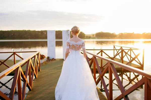 Красива наречена стоїть на пірсі під час заходу сонця — стокове фото