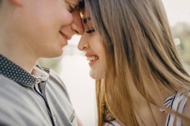 Gün batımında genç ve güzel bir çift öpüşür. Sevgililer Günü 'nün kollarında genç bir çift, harika bir ruh hali, genç insanlar güler.