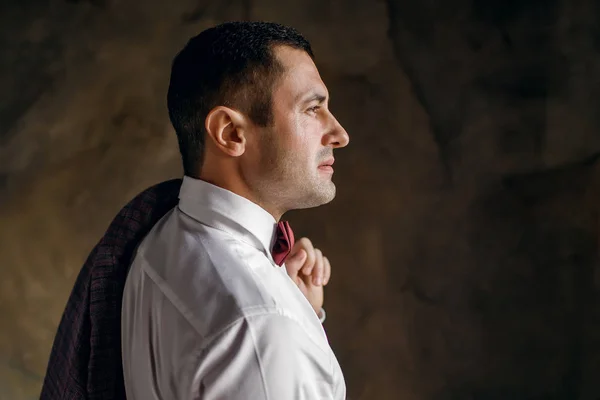 Yakışıklı, şık bir adam taştan bir duvara bakıyor.