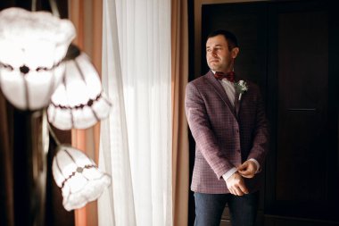 Yakışıklı, kendine güvenen bir adam ceket giyer, damat düğün gününde toplanır.