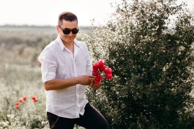 Siyah gözlüklü genç bir adam, 8 Mart ya da 14 Şubat 'ta bir buket lale taşıyor.