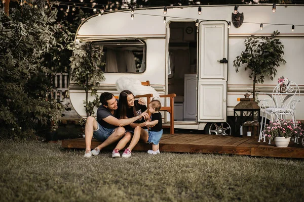 Karavanın yanındaki genç aile, baba, anne ve kızı bir karavanda yaşıyor.
