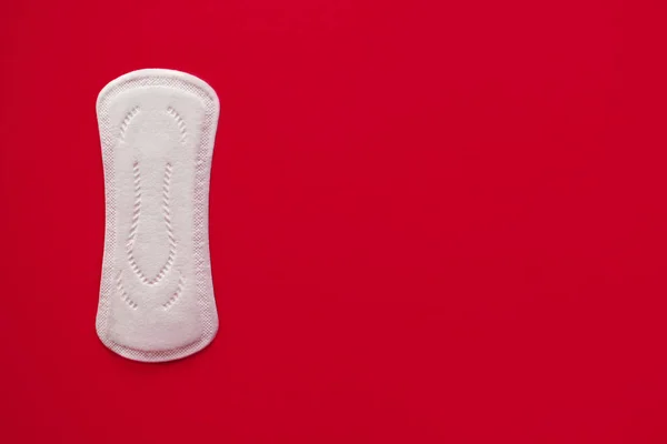 Una almohadilla menstrual sobre un fondo rojo, vista superior, lugar para el texto —  Fotos de Stock