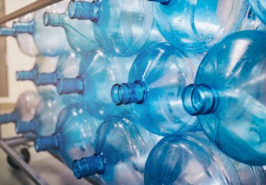 Plastik şişelerin arka planı, yıkama ve işleme plastiği hazırlığı, bir su üretim tesisi, arıtılmış su içme, birçok plastik şişe üst üste istiflenmiştir