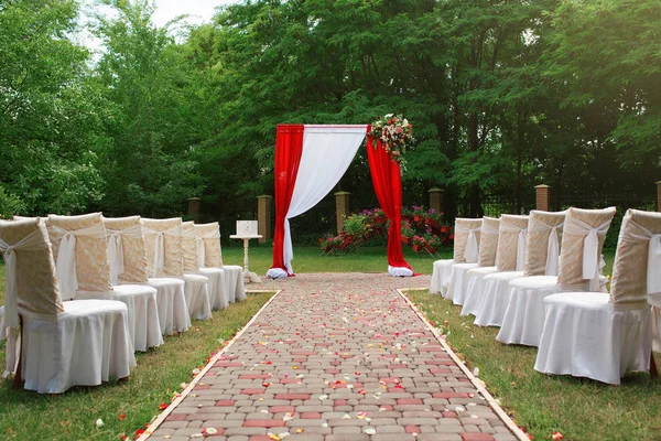 漂亮的婚礼拱门 装饰着鲜花 客人用的白色椅子 玫瑰花瓣 举行婚礼的漂亮公园 完美的婚礼 — 图库照片