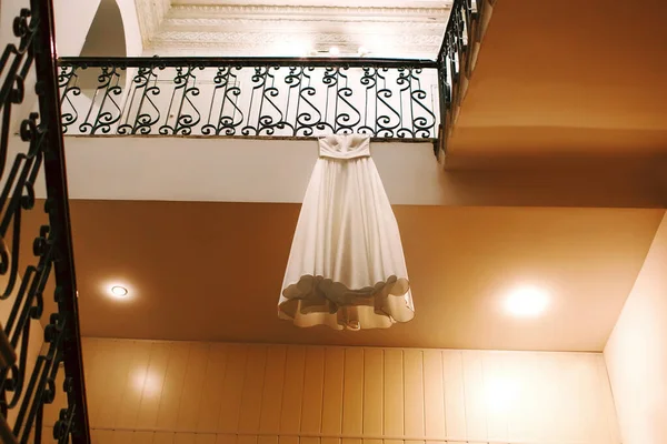 beautiful brides wedding dress, white designer dress hanging on the stairs, creative photo of the wedding dress, entrance of the old building
