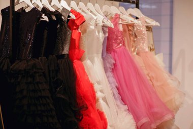 Askıda kadın elbiseleri, ticaret katında çok renkli elbiseler, moda giysileri, parlak kadın kıyafetleri, arka planda elbiseler.