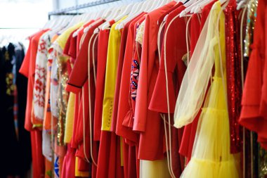 Askıda kadın elbiseleri, ticaret katında çok renkli elbiseler, moda giysileri, parlak kadın kıyafetleri, arka planda elbiseler.