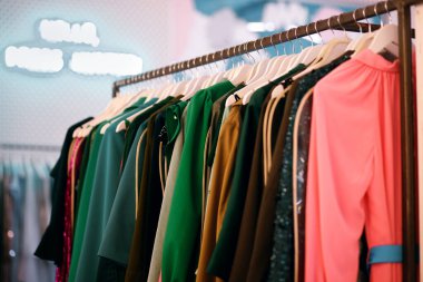 Askıda kadın elbiseleri, ticaret katında çok renkli elbiseler, moda giysileri, parlak kadın kıyafetleri, arka planda elbiseler.