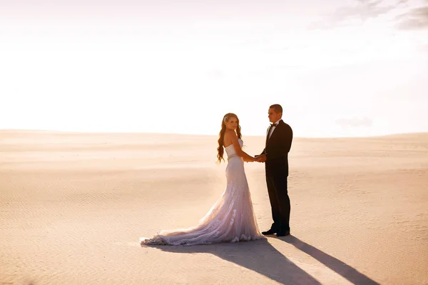 Menyasszony Vőlegény Fogják Egymás Kezét Homokos Sivatagban Napnyugtakor Egy Gyönyörű — Stock Fotó