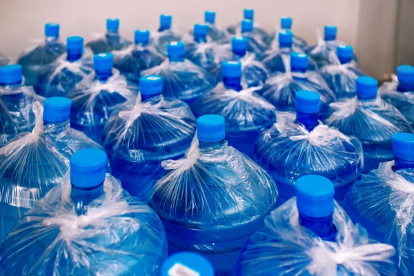 Soğutucu için bir sıra büyük şişe içme suyu. Su teslimatı. Paketlendi ve müşterilere gönderilmeye hazır. Mavi şişeler, bitmiş eşyalar deposu, temiz su.