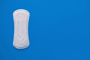 Mavi arka planda bir adet pedi, üst görünüm, yazı için bir yer, kadınlar için kan emici, kritik günler, medikal pedler, kadın aksesuar