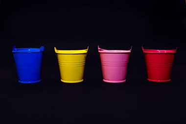 Metin, mavi, sarı, pembe ve kırmızı kovalar, bahçıvanlık konsepti, siyah üzerine renklendirilmiş dört renkli kova.