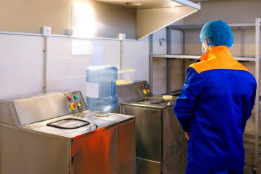 Bir içme suyu arıtma tesisi, bir fabrika işçisi plastik şişeyi inceler, temizliği izler, içme suyu tesisi, plastik işleme, temiz su sağlık garantisidir