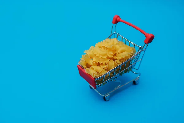 Pasta Een Mini Boodschappenkarretje Blauwe Achtergrond Plaats Voor Tekst Concept — Stockfoto