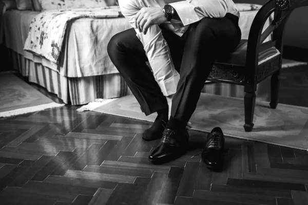 一个生意人把鞋带系在鞋子的特写上 男人的手和一双皮鞋 商人的早晨 在一张黑白相间的照片中 新郎在酒店房间里穿衣 — 图库照片